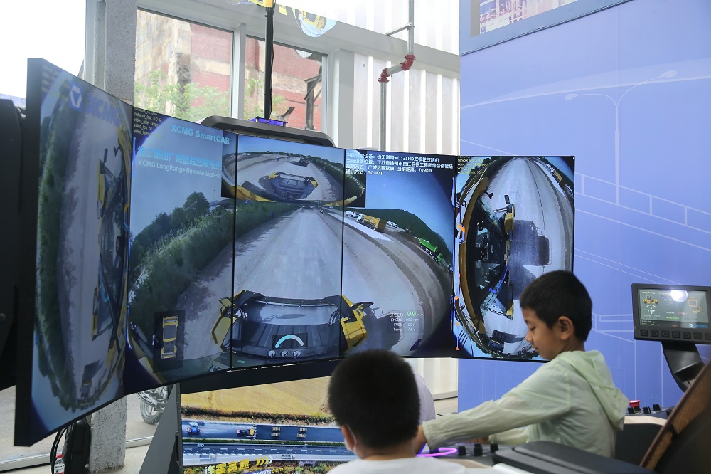 坐在徐工集团广域远程驾驶系统的模拟驾驶舱，可以通过操作方向盘、油门、刹车等透过大屏幕看到作业情景。